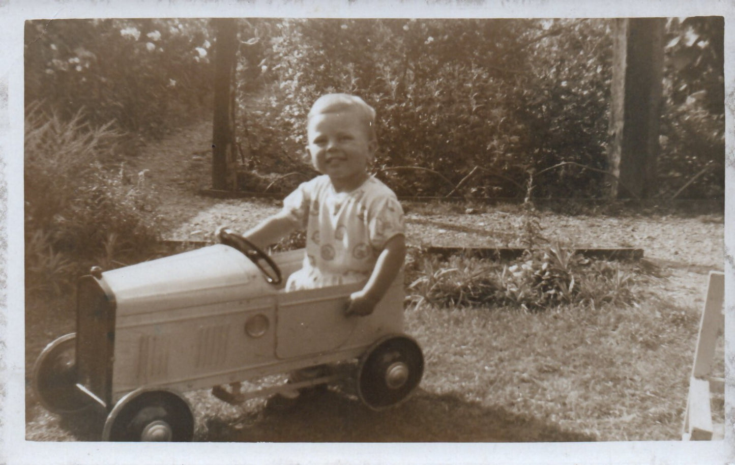Real Photo of Little Child Playing in a Toy Pedal Car Postcard