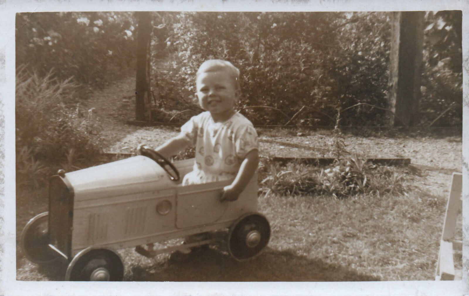 Real Photo of Little Child Playing in a Toy Pedal Car Postcard