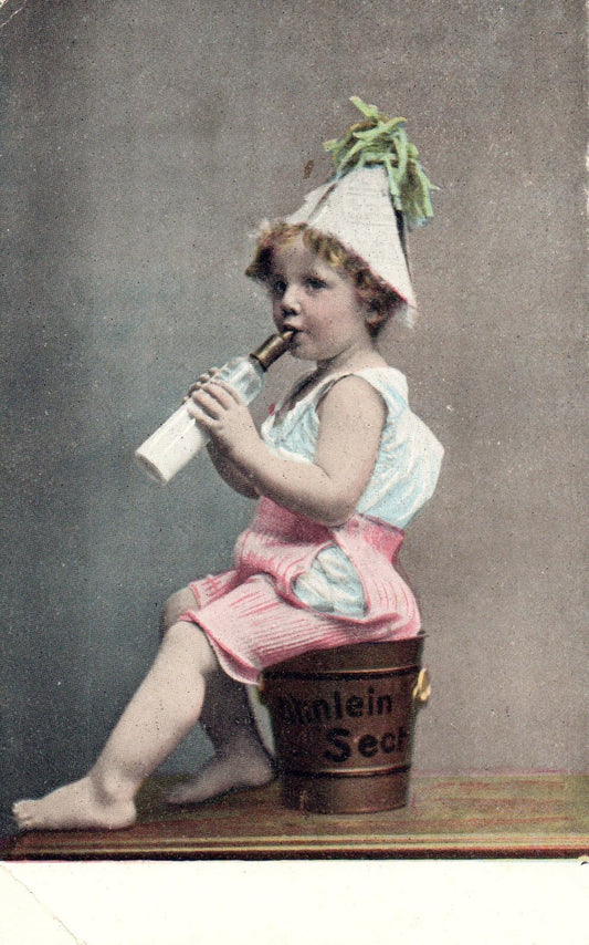 Child in hat sitting on a bucket drinking milk out of a bottle Children Postcard