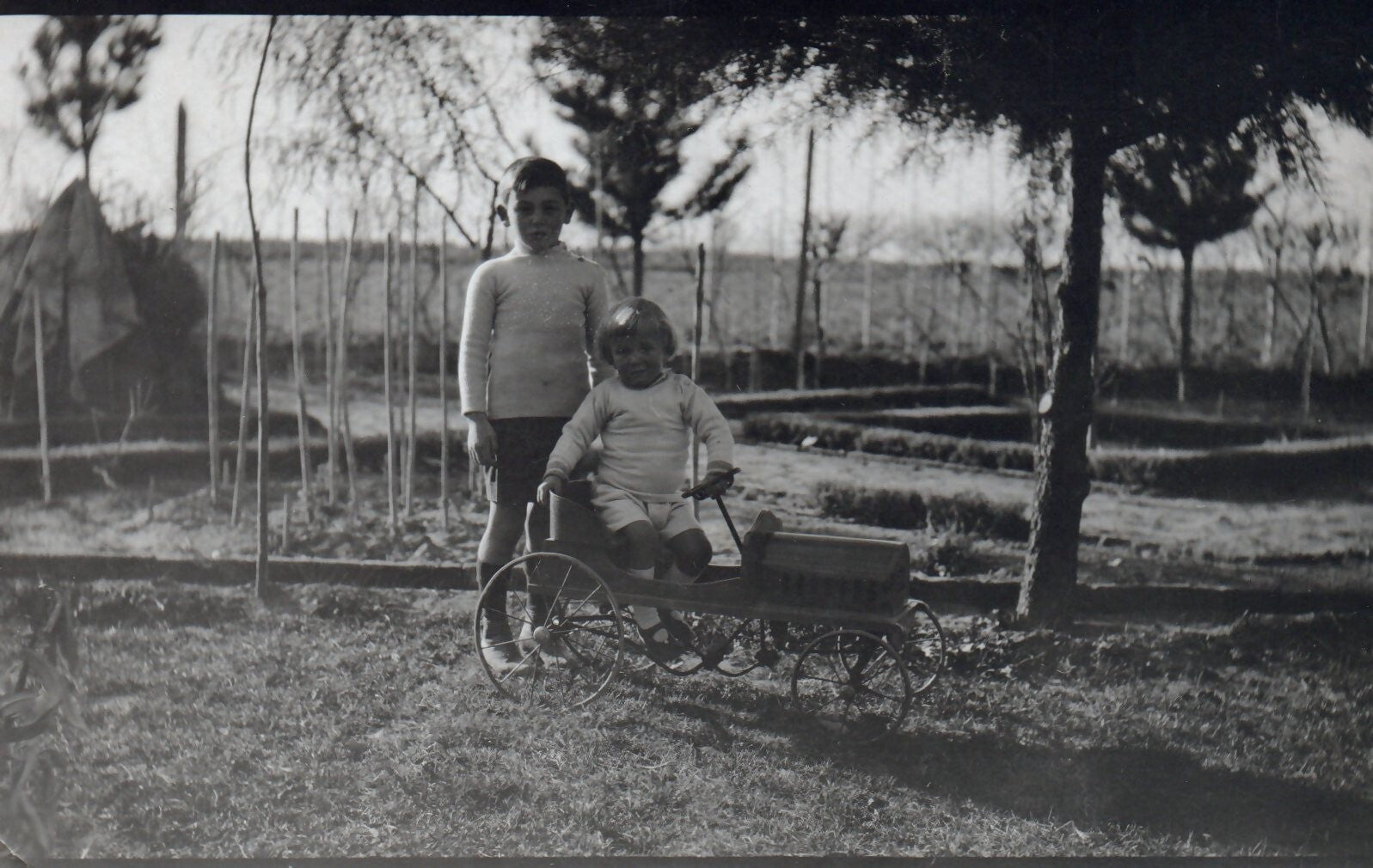 Real Photo Two Young Children Playing with an Old Toy Pedal Car Postcard