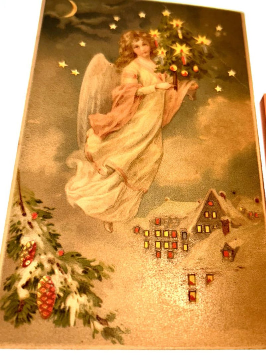 Angel Holding Miniature Christmas Tree Above a SNow Covered House